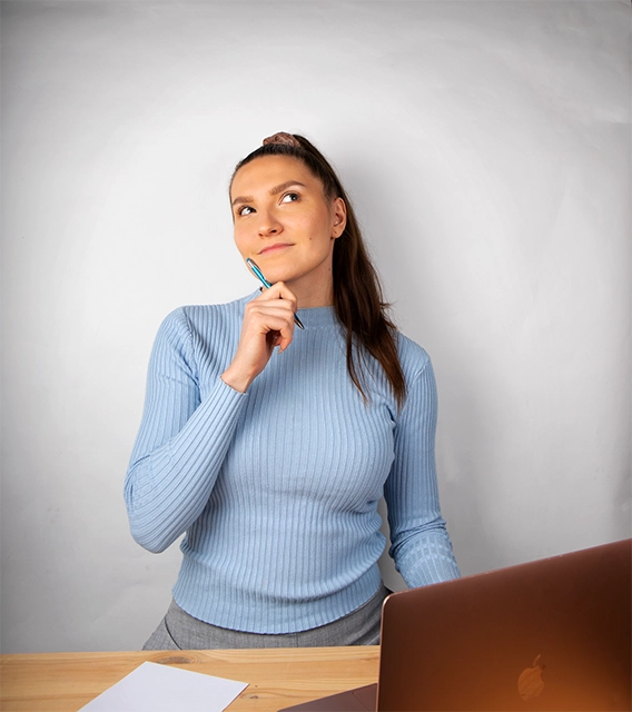 Digimarkkinoinnin freelancer Pia Kojo katsomassa mietteliäällä ilmeellä yläviistoon työpöytänsä ääressä.