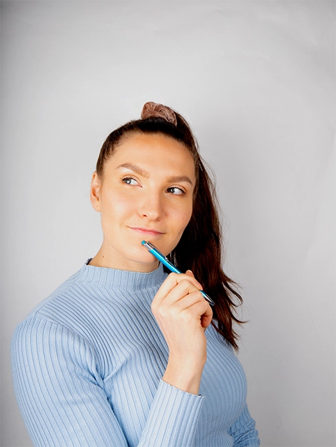 Freelancer Pia Kojo miettivällä ilmeellä kynä kädessä.