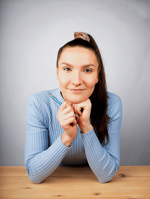 Digimarkkinoinnin freelancer Pia Kojo katsomassa kameraan kädet pöydällä.